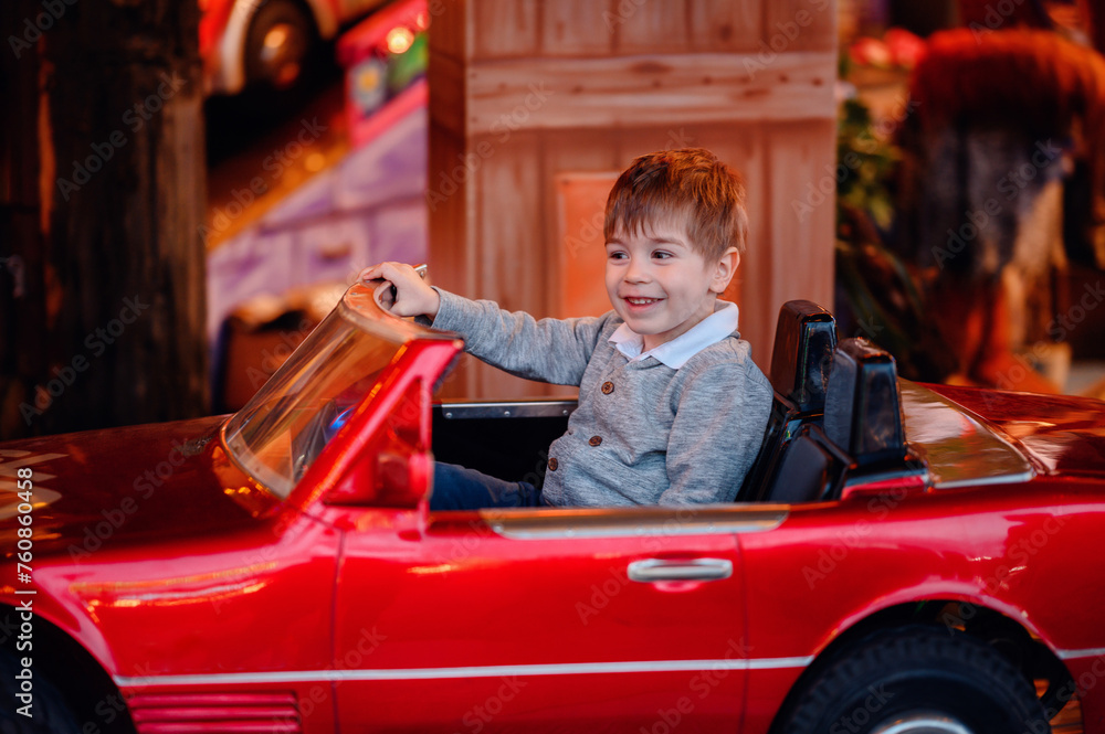 A cheerful toddler beams as he takes the wheel of a bright red convertible on a merry-go-round, encapsulating the thrill of a child's first drive A cheerful toddler beams as he takes the wheel of a bright red convertible on a merry-go-round, encapsulating the thrill of a child's first drive