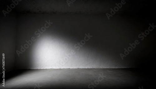 A dark, empty room with a grey wall. The room is empty and has no furniture. The walls are bare and the floor is covered in dirt