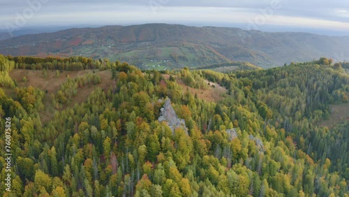Bird's eye view of the Carpathians in autumn, Ukraine. Huge rocks scattered picturesquely along the mountain slopes, houses, colorful beech, birch and coniferous forests photo
