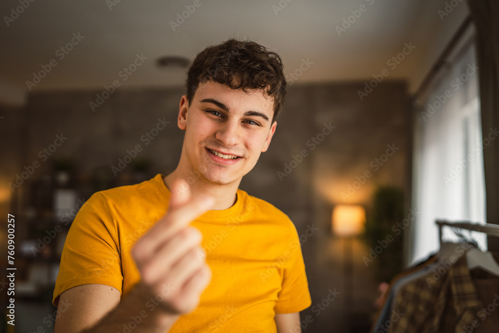 Portrait of one caucasian man 20 years old looking to the camera at home smiling show hand hart gesture Portrait of one caucasian man 20 years old looking to the camera at home smiling show hand hart gesture