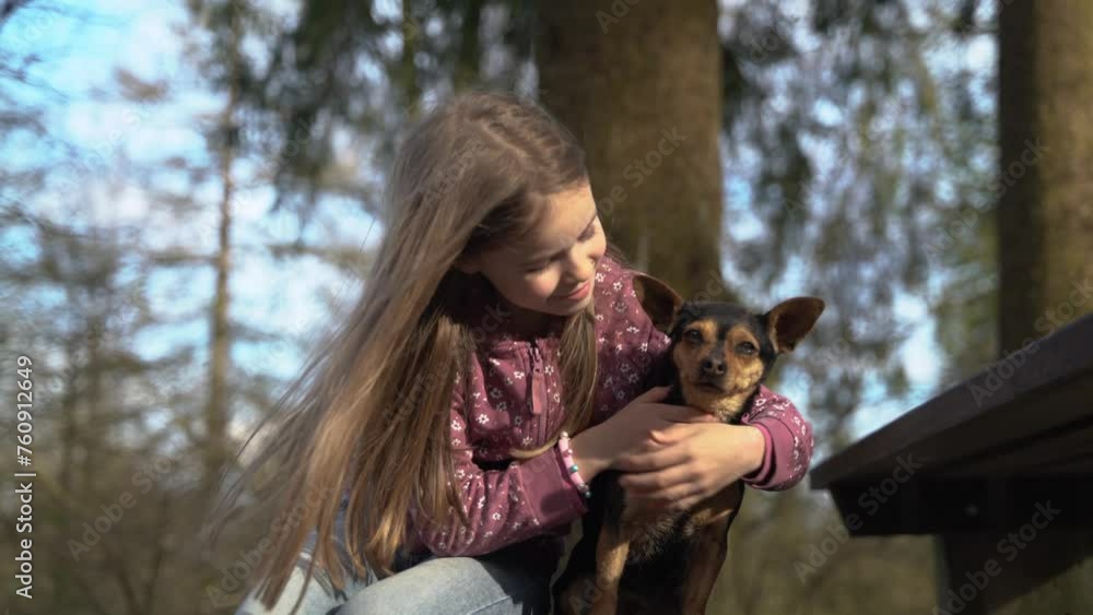 Girl hugging and petting a small black dog