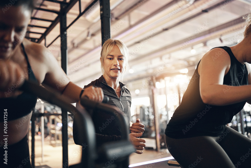 Female instructor shouting encouragement to a group of young women working out on crosstrainers during an exercise class at the gym Female instructor shouting encouragement to a group of young women working out on crosstrainers during an exercise class at the gym