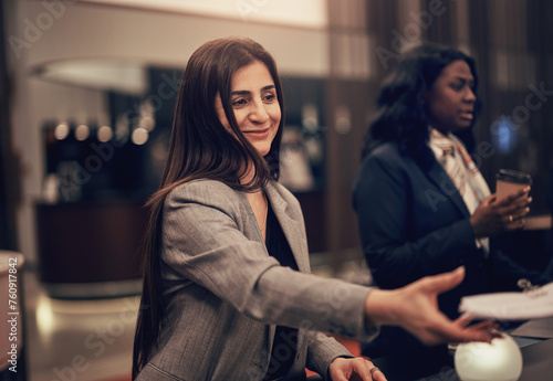 Smiling diverse businesswoman working with colleagues in the lobby of a hotel photo
