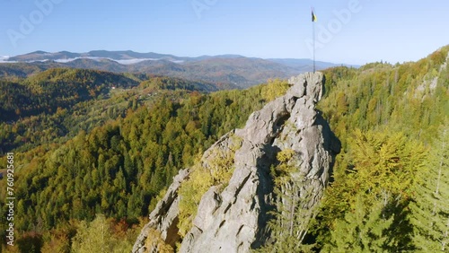 Bird's eye view of the Carpathians in autumn, Ukraine. Huge rocks scattered picturesquely along the mountain slopes, houses, colorful beech, birch and coniferous forests photo