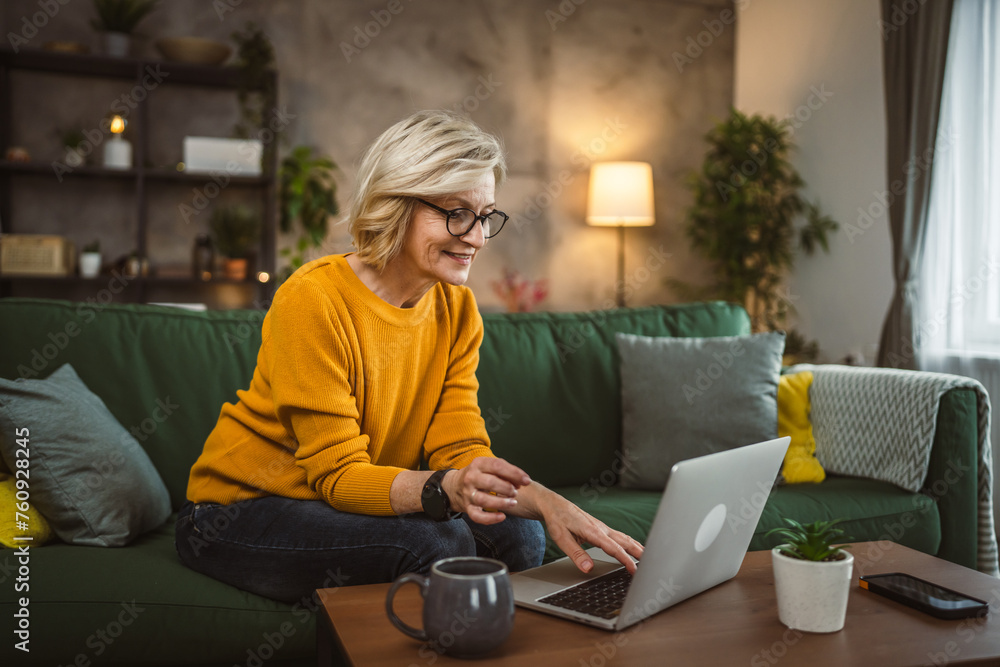Obraz premium Mature blonde caucasian woman use laptop computer at home for work