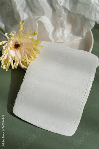 Overhead view of a Blank piece of handmade card on a ceramic plate with gerbera and crumpled paper photo