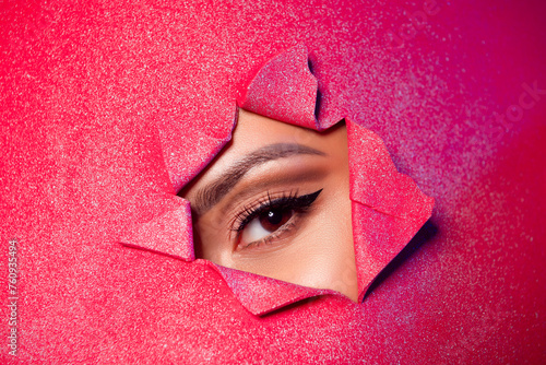Photo of girl look through torn red glitter bright paper billboard with eye liner cosmetics