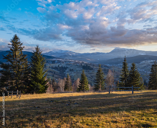 Late autumn mountain pre sunset scene with snow covered tops in far. Picturesque traveling, seasonal, nature and countryside beauty concept scene. Carpathians, Ukraine.