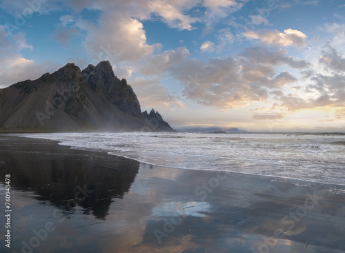Sunrise Stokksnes cape sea beach and Vestrahorn Mountain with its reflection on wet black volcanic sand surface, Iceland. Amazing nature scenery, popular travel destination.