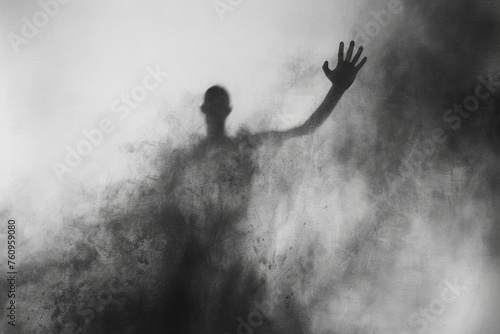 A man is silhouetted against a dark background, with his hand raised in the air photo
