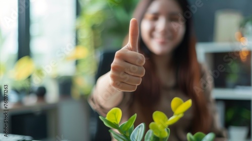 Thumbs up sign. Woman's hand shows like gesture. Home office background