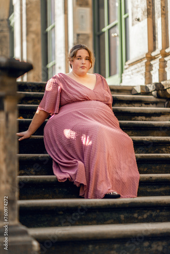 Fényképezés A young plus size woman wearing a pink dress dancing in the street of a city