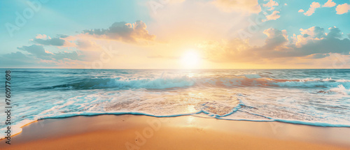 Sunset casting golden light over the ocean with waves approaching the sandy beach under a cloud-filled sky. © Enigma