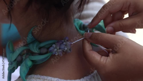 Close-up of a woman making lei in Hawaii, plumeria flowers garland crown handmade.