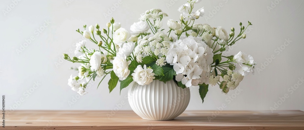 A fresh and cheerful display of white spring flowers arranged in a classic white vase on a wooden table against a white background. - obrazy, fototapety, plakaty 
