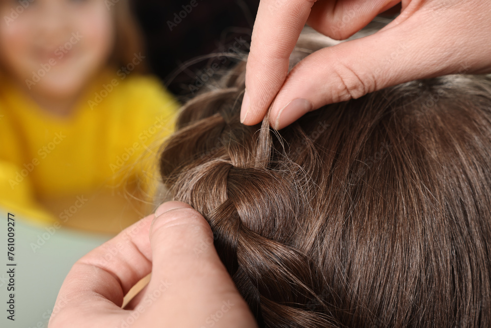 Professional stylist braiding girl's hair indoors, closeup Professional stylist braiding girl's hair indoors, closeup