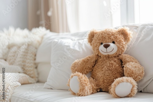 Plush teddy bear sitting on white couch with pillows