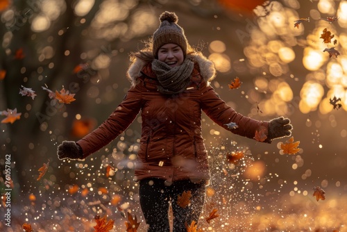 A woman in a winter jacket playing with autumn leaves.