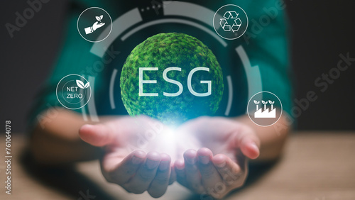 A person is holding a globe with the letters ESG on it