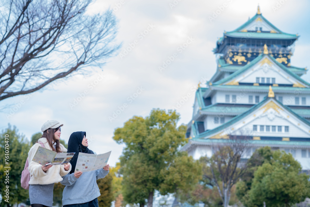 Obraz premium Travel, muslim travel, woman girl tourist Two Asian friends but different religions walking at Osaka Castle, Osaka Castle is one of the most famous landmarks in Japan and Osaka, holiday lifestyle.