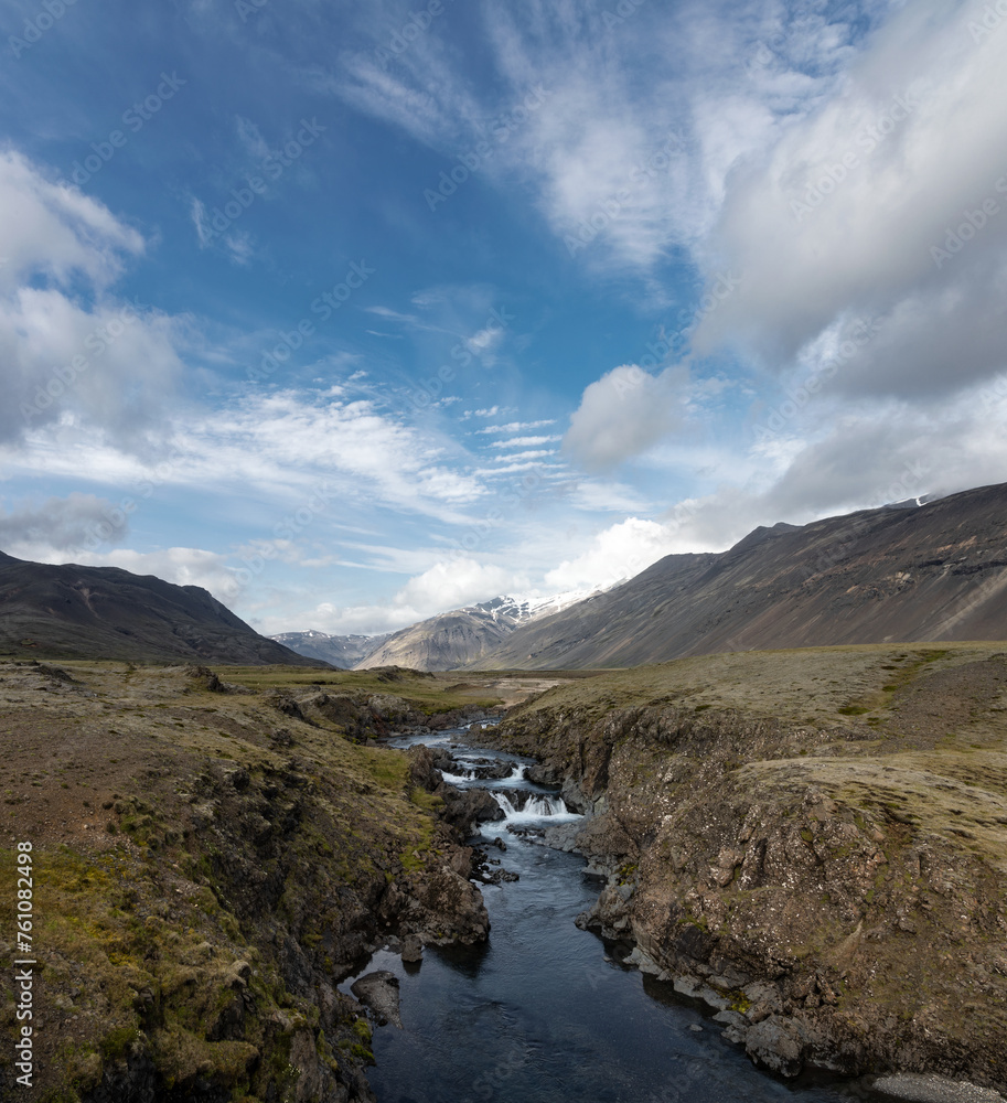 Flowing river, blue sky and mountains in the highlands of Iceland