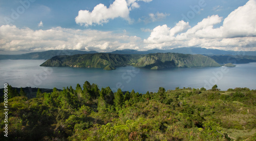 Aerial view of volcanic lake Toba and surrounding mountains and tropical green hills during sunny day in Samosir island, Sumatra island, Indonesia
