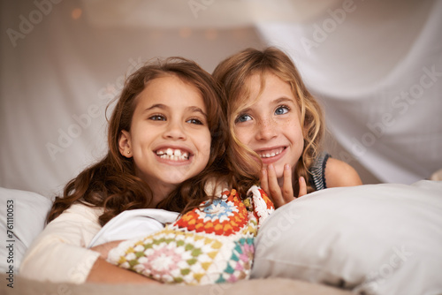 Happy, sleepover and face of children in bedroom for playing, bonding and relax with toys in home. Laughing, friends and young girls on bed in tent or blanket fort for childhood, fun and happiness photo