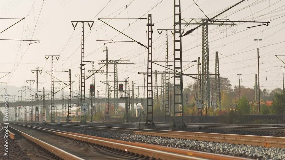 Sunset glow on railway tracks with complex overhead wiring and signals, no trains visible, empty rails Sunset glow on railway tracks with complex overhead wiring and signals, no trains visible, empty rails