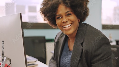 African american coworker smiling at camera sitting in the office
