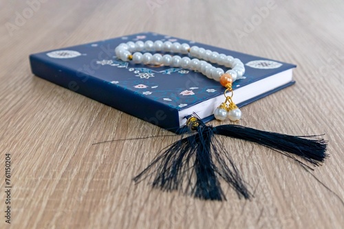 A Surah Yaseen or Yasin book and prayer beads on a wooden table photo