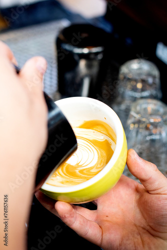 closeup shot pouring hot milk into cup with espresso to make latte art