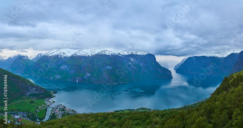 beautiful and tranquil landscape of the Aurlandsfjord near Flam, seen from the Stegastein view point high above with snow covered mountain peaks in the background.