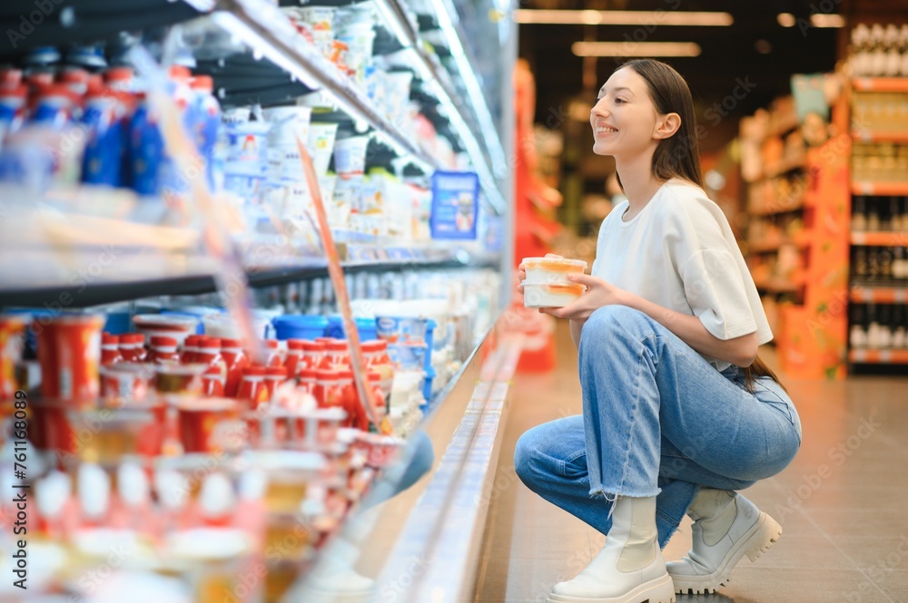 Happy young woman looking at product at grocery store. Smiling woman shopping in supermarket