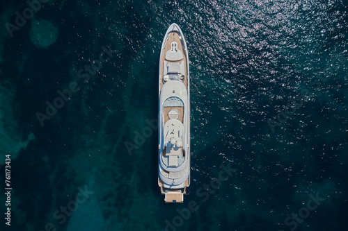 A large expensive white yacht is anchored, top view. White yacht Turquoise water air view. White large Mega yacht on azure water aerial view.