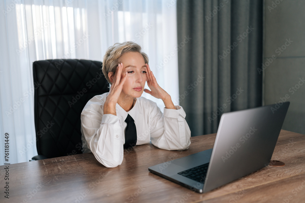 Fatigued stressful female entrepreneur 50s reading bad news in laptop. Sad concerned middle-aged business woman thinking problem solution worry anxiety difficulties business data failure. Fatigued stressful female entrepreneur 50s reading bad news in laptop. Sad concerned middle-aged business woman thinking problem solution worry anxiety difficulties business data failure.