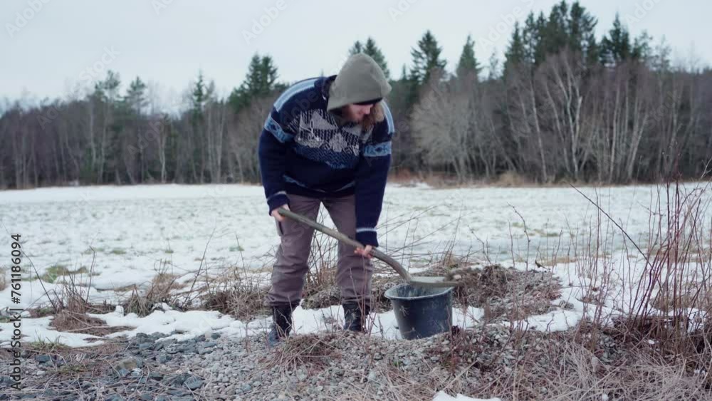 A Man is Filling a Bucket with Soil and Gravel for Use in a DIY Hot Tub - Static Shot A Man is Filling a Bucket with Soil and Gravel for Use in a DIY Hot Tub - Static Shot