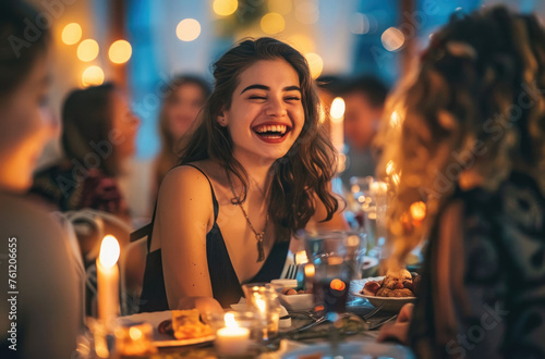 Photo of a beautiful woman laughing at a table during dinner in a restaurant, holding food with her hand and showing it to friends, wearing a black dress and diamond necklace
