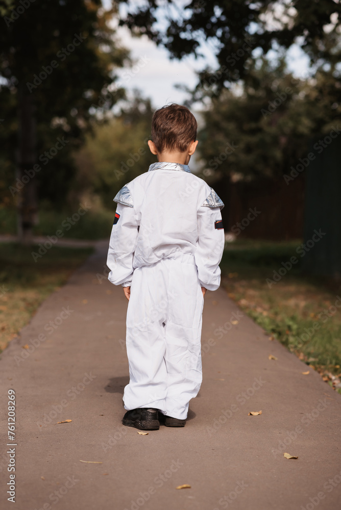 A little boy in an astronaut costume is playing outside on a sunny day. Vertical photo. A little boy in an astronaut costume is playing outside on a sunny day. Vertical photo.