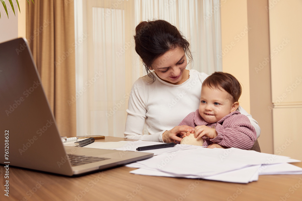 Cheerful pretty businesswoman working at home with her little child girl Cheerful pretty businesswoman working at home with her little child girl