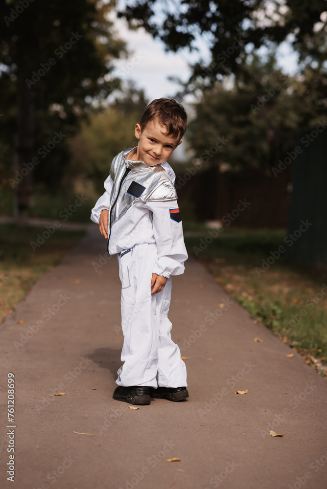 A little boy in an astronaut costume is playing outside on a sunny day. Vertical photo. A little boy in an astronaut costume is playing outside on a sunny day. Vertical photo.