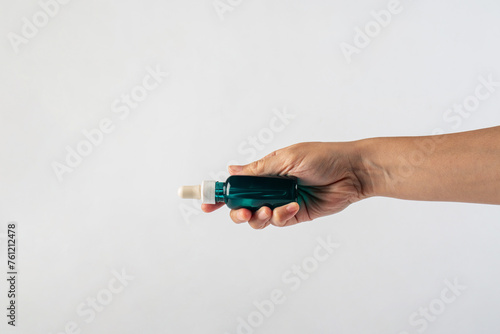 Blue glass cosmetic bottle, Skin care or sunscreen cosmetic with hand on white background.
