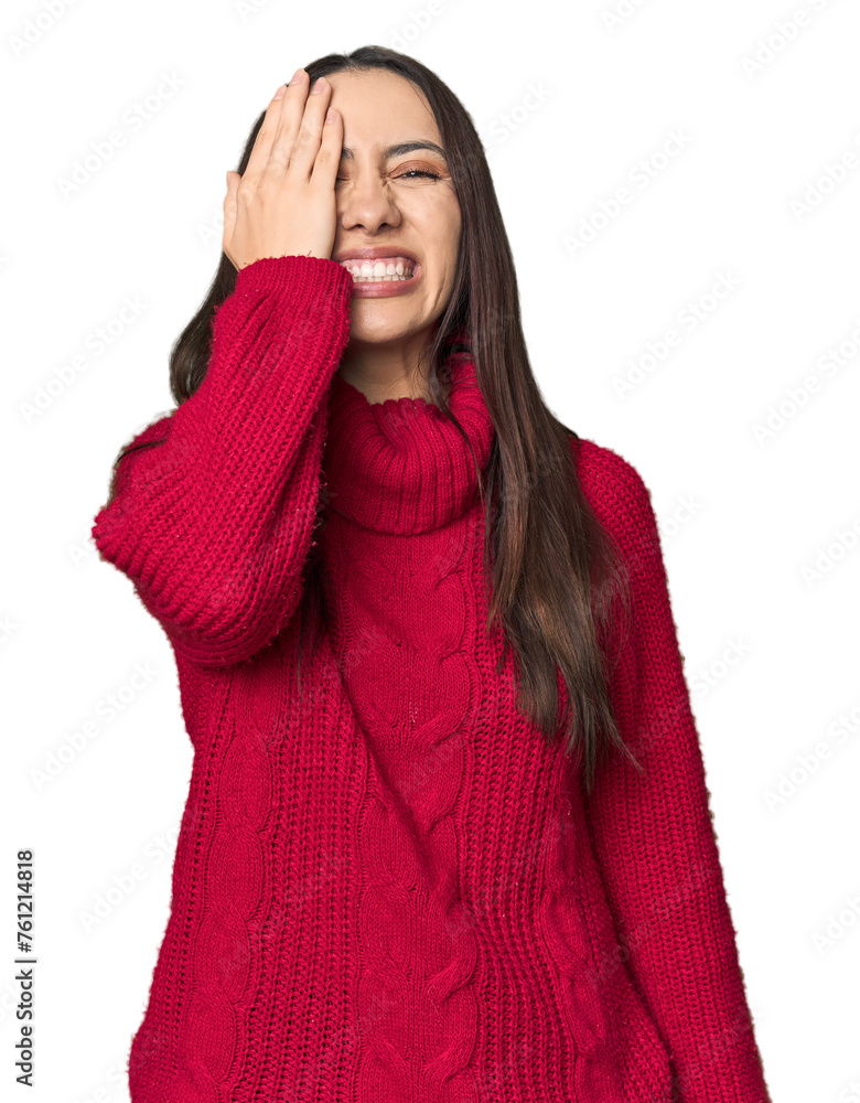 Young Caucasian woman in cozy red sweater on studio background having fun covering half of face with palm. Young Caucasian woman in cozy red sweater on studio background having fun covering half of face with palm.