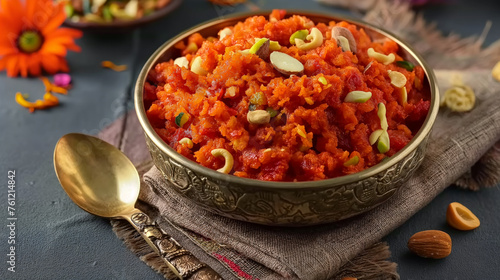 Gajar ka Halwa served in a traditional metal bowl with nuts, styled spoon, on dark background photo
