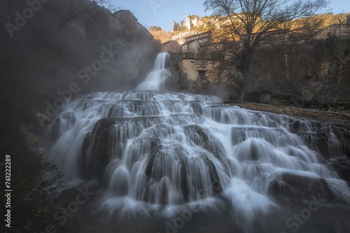 First hours of the day at the Orbaneja del Castillo waterfall  Burgos  a winter day with the waterfall full of water and some mist creating an atmosphere