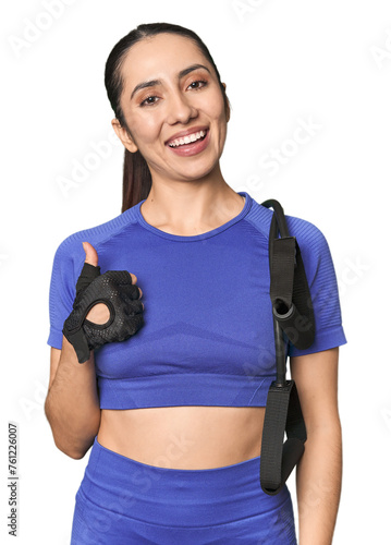 Athletic young Caucasian woman with resistance band on studio background smiling and raising thumb up