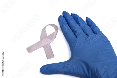 Dłoń w niebieskiej rękawicy obok rozowej wstazki, walka z rakiem, białe tlo