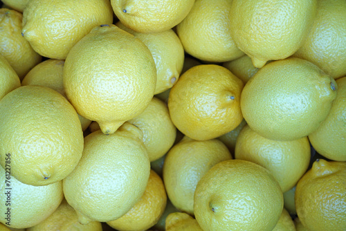 Close up piles of organic yellow lemon citrus fruit on supermarket display shelf