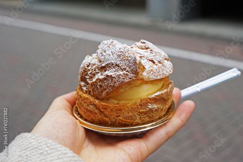 Close up hand holding vanilla Choux cream puff, French pastry dessert