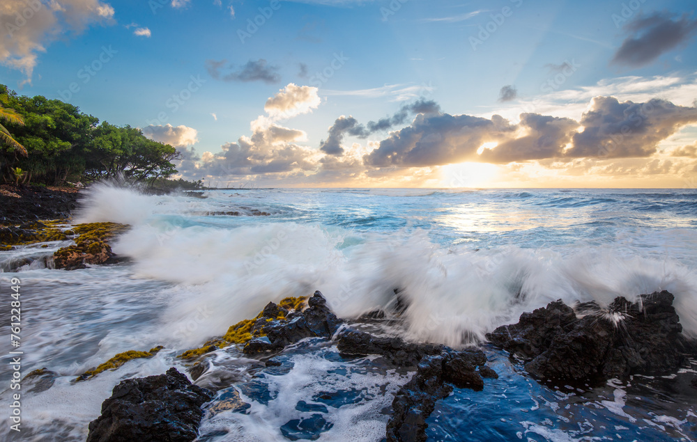 Fototapeta premium Sunset over the sea, waves crashing on the rocks, palm trees on the beach in Hawaii. Big Island, United States of America.