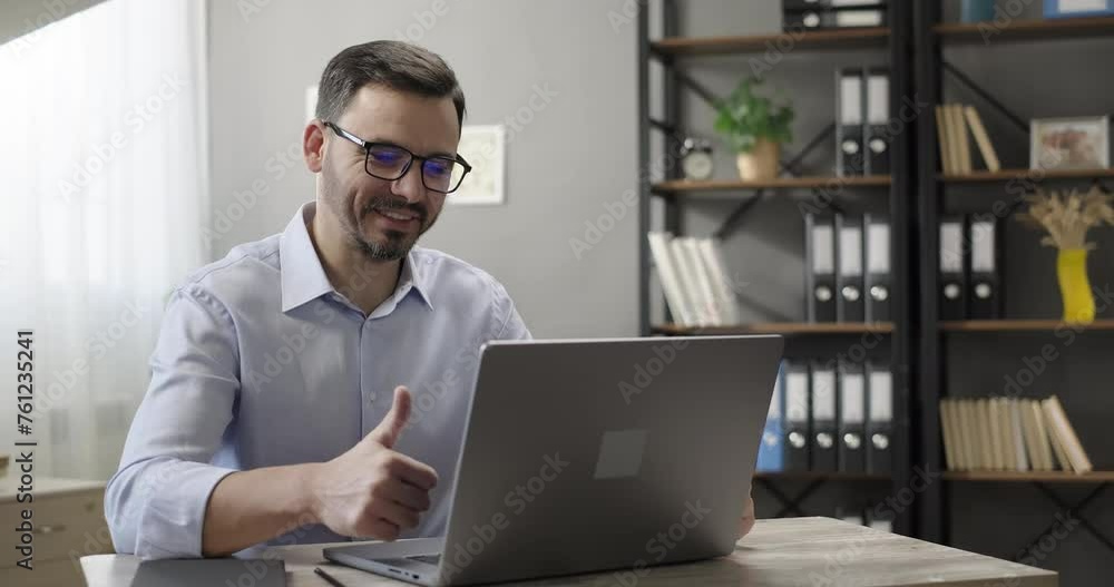 Smiling businessman talking receiving good news during online conference video chat call team meeting, showing thump-up gesture, celebrating success, using laptop. Partnership, deal agreement Smiling businessman talking receiving good news during online conference video chat call team meeting, showing thump-up gesture, celebrating success, using laptop. Partnership, deal agreement
